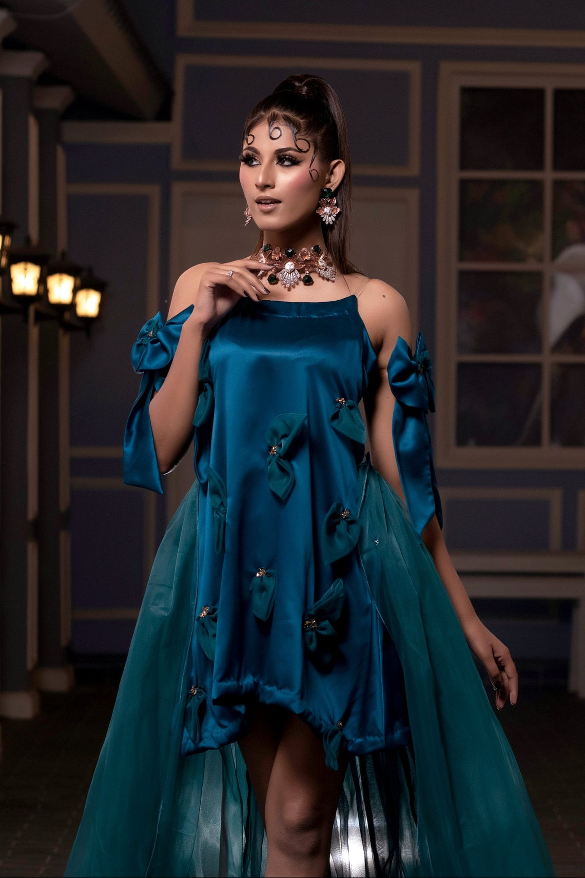 Woman in a blue dress standing in an indoor setting with decorative elements.