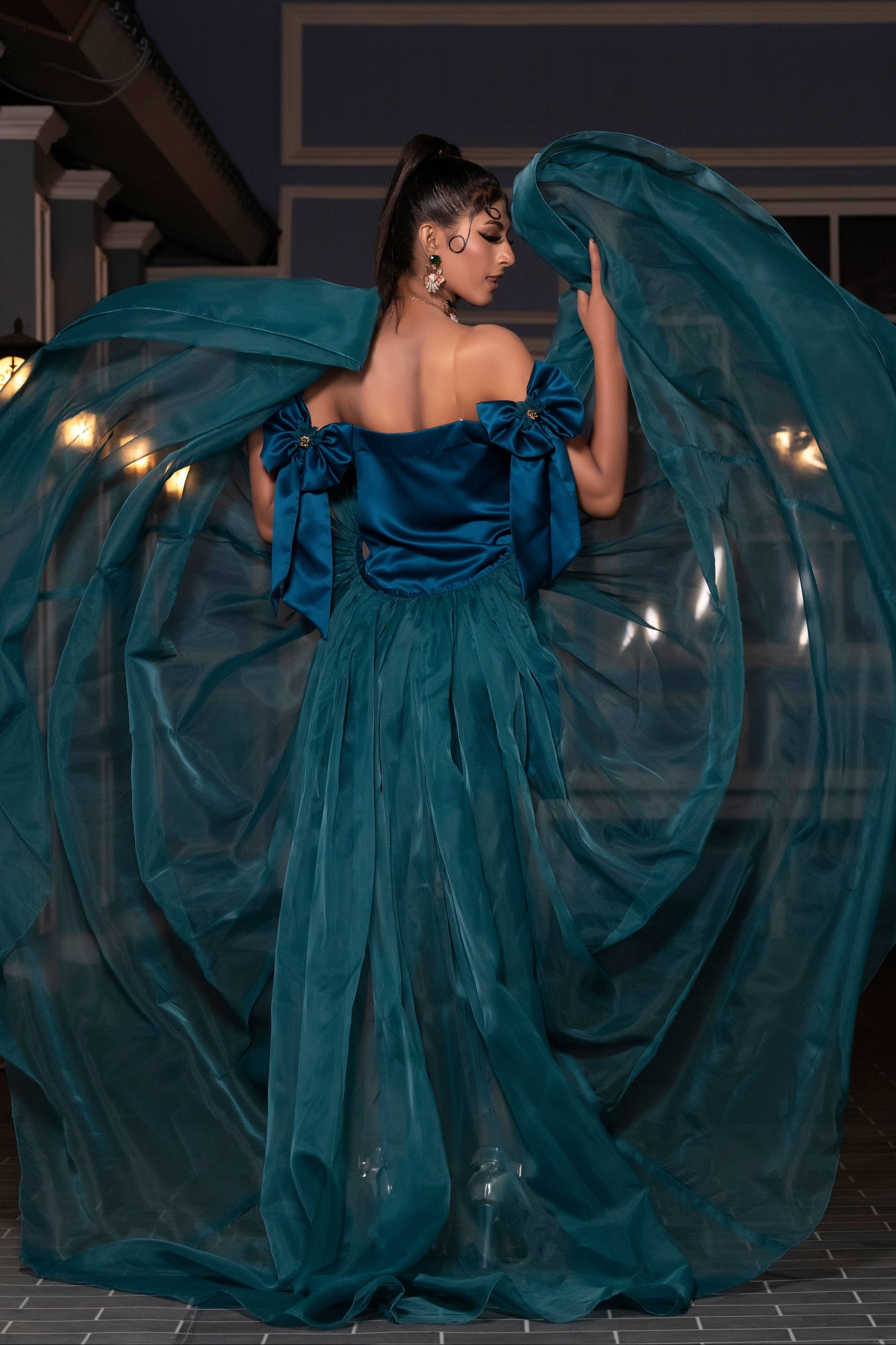 Woman in a flowing teal dress with a dark background
