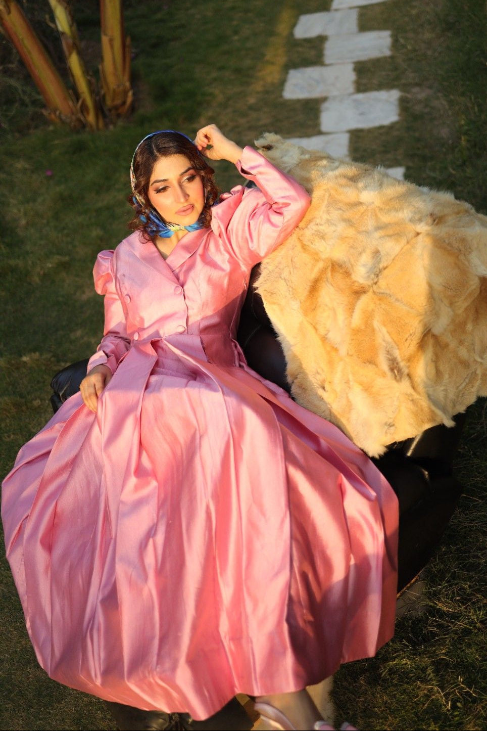Woman in a pink dress sitting on grass with a white path in the background