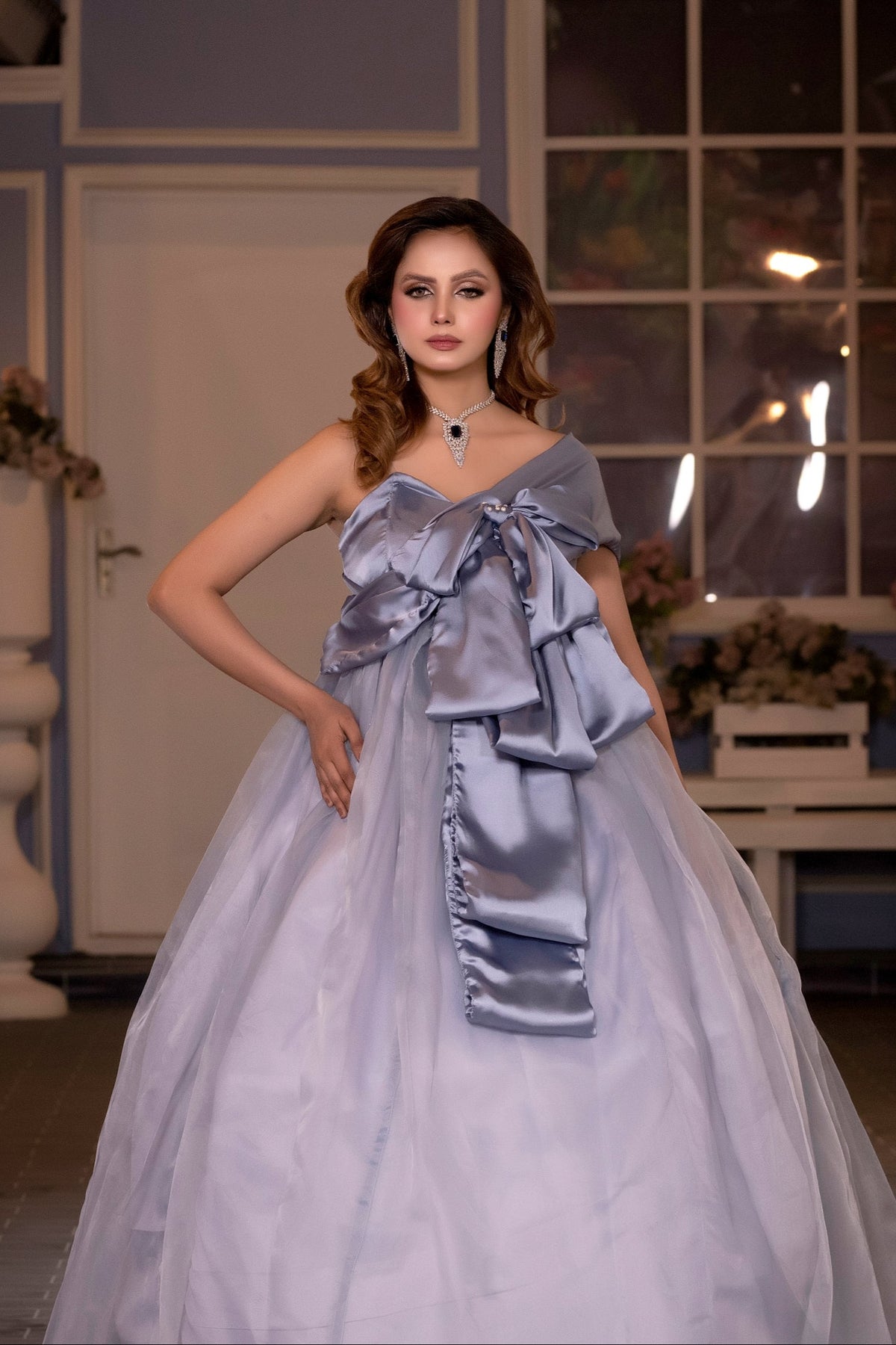Woman in a light purple gown with a large bow standing indoors.