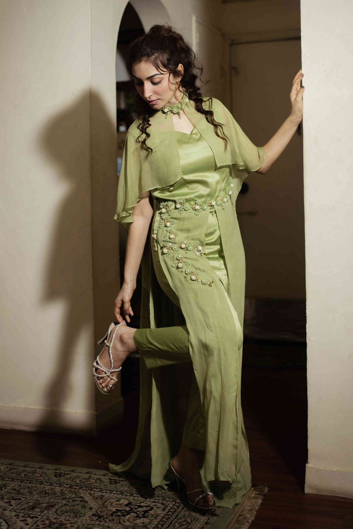 Woman in a green outfit standing in a doorway.