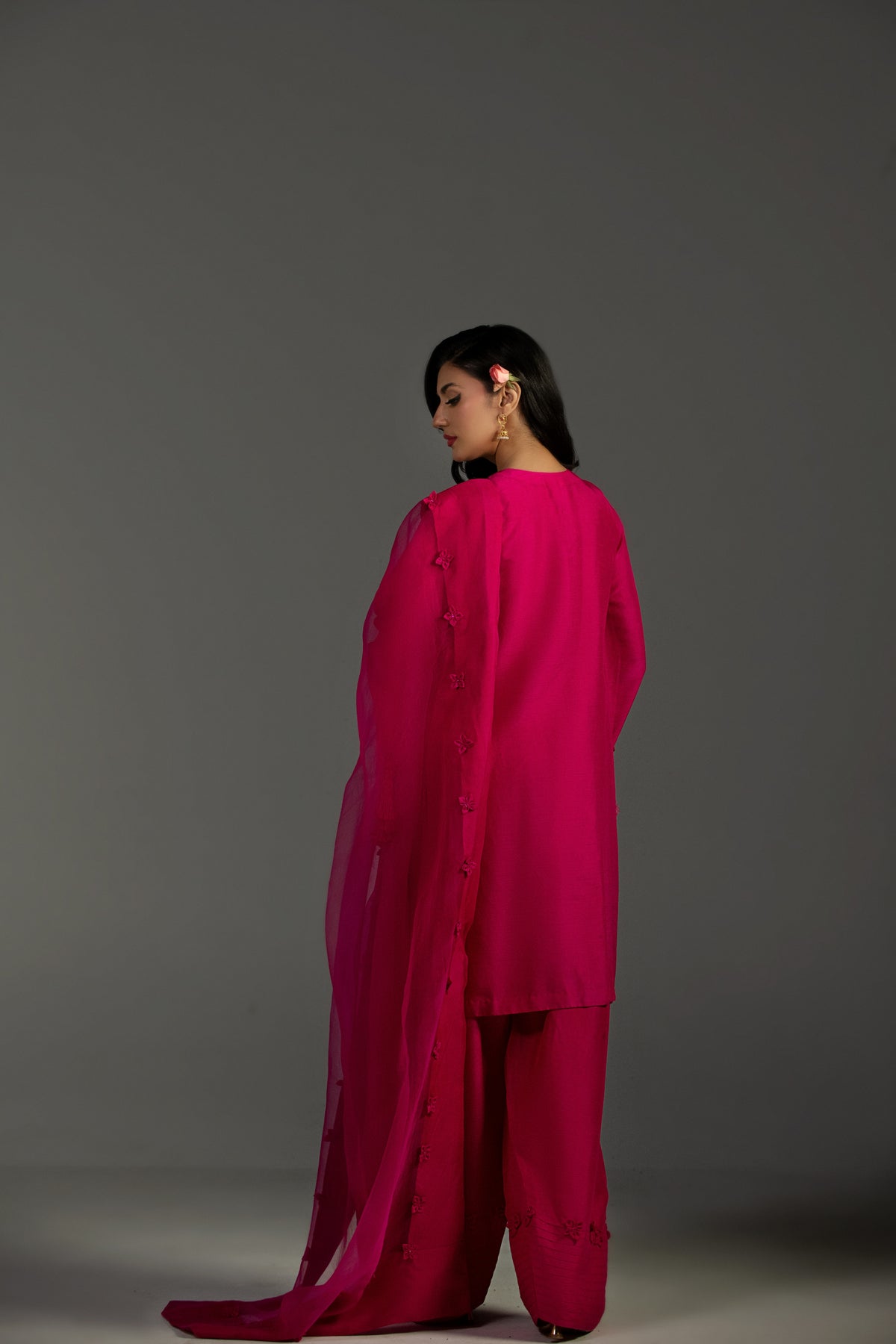 Woman wearing a bright pink outfit against a gray background