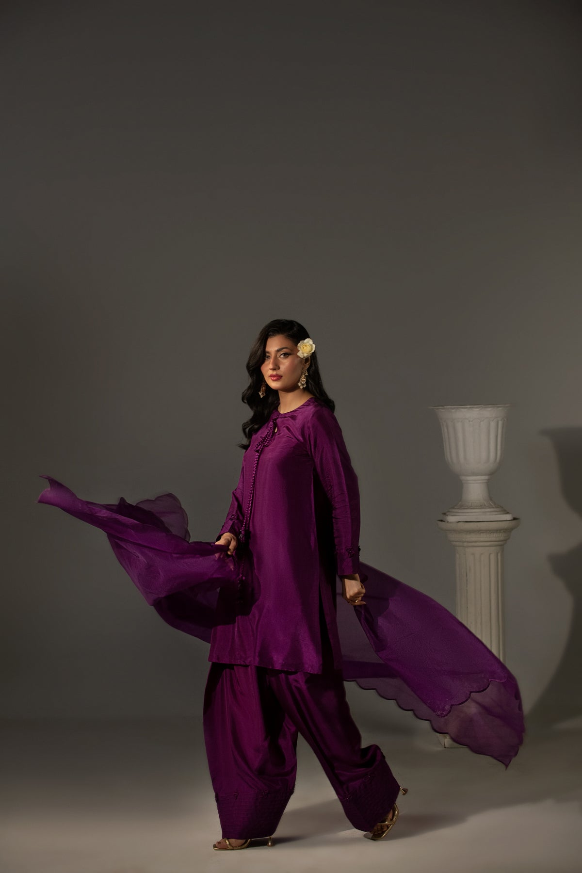 Woman in a flowing purple outfit against a gray background