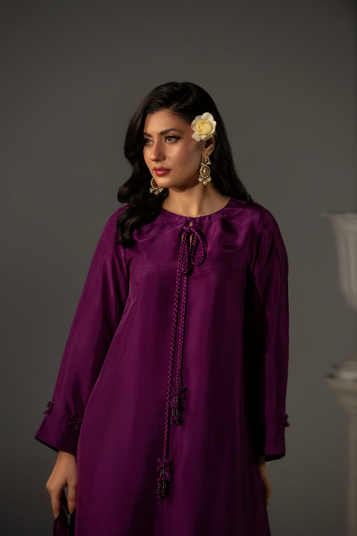 Woman wearing a purple dress with decorative elements against a gray background