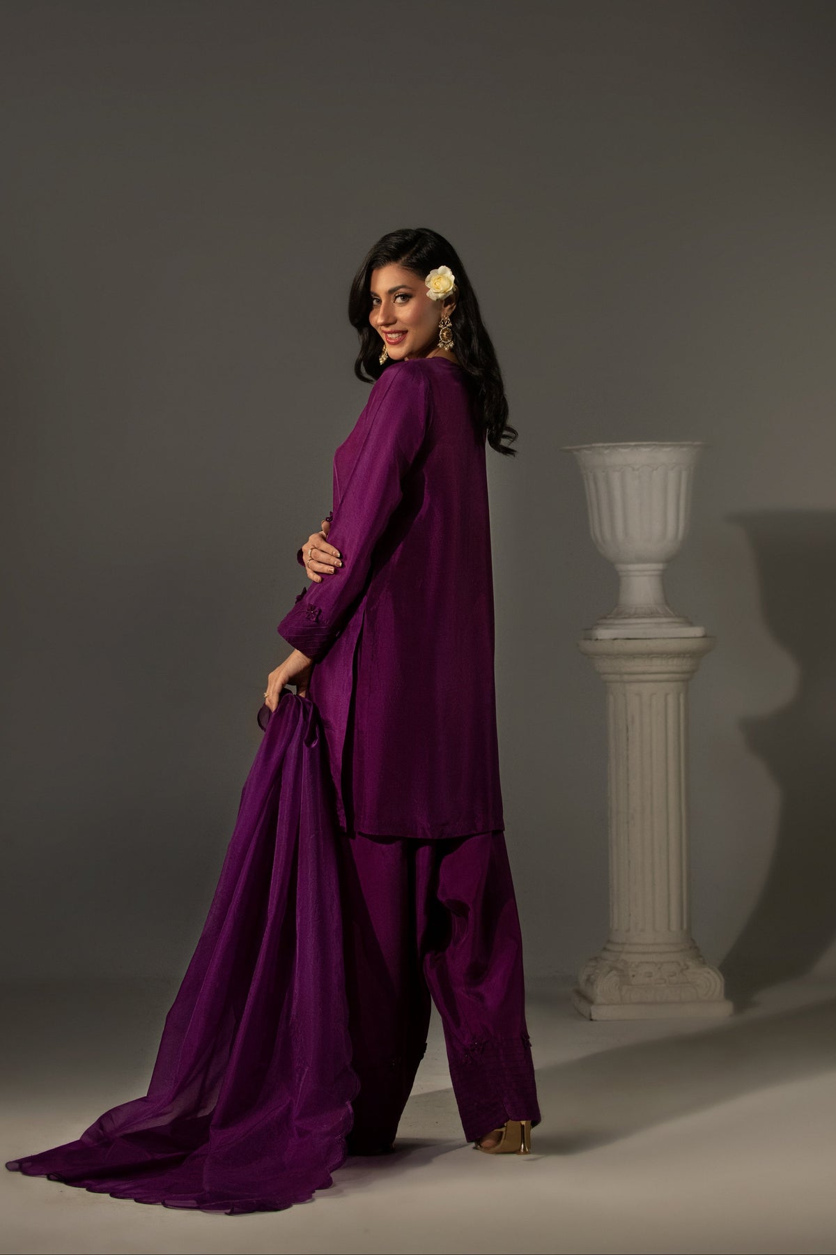 Woman in a purple outfit standing against a gray background