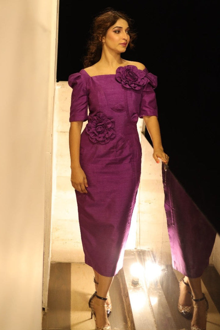 Woman in a purple dress standing in front of a mirror.