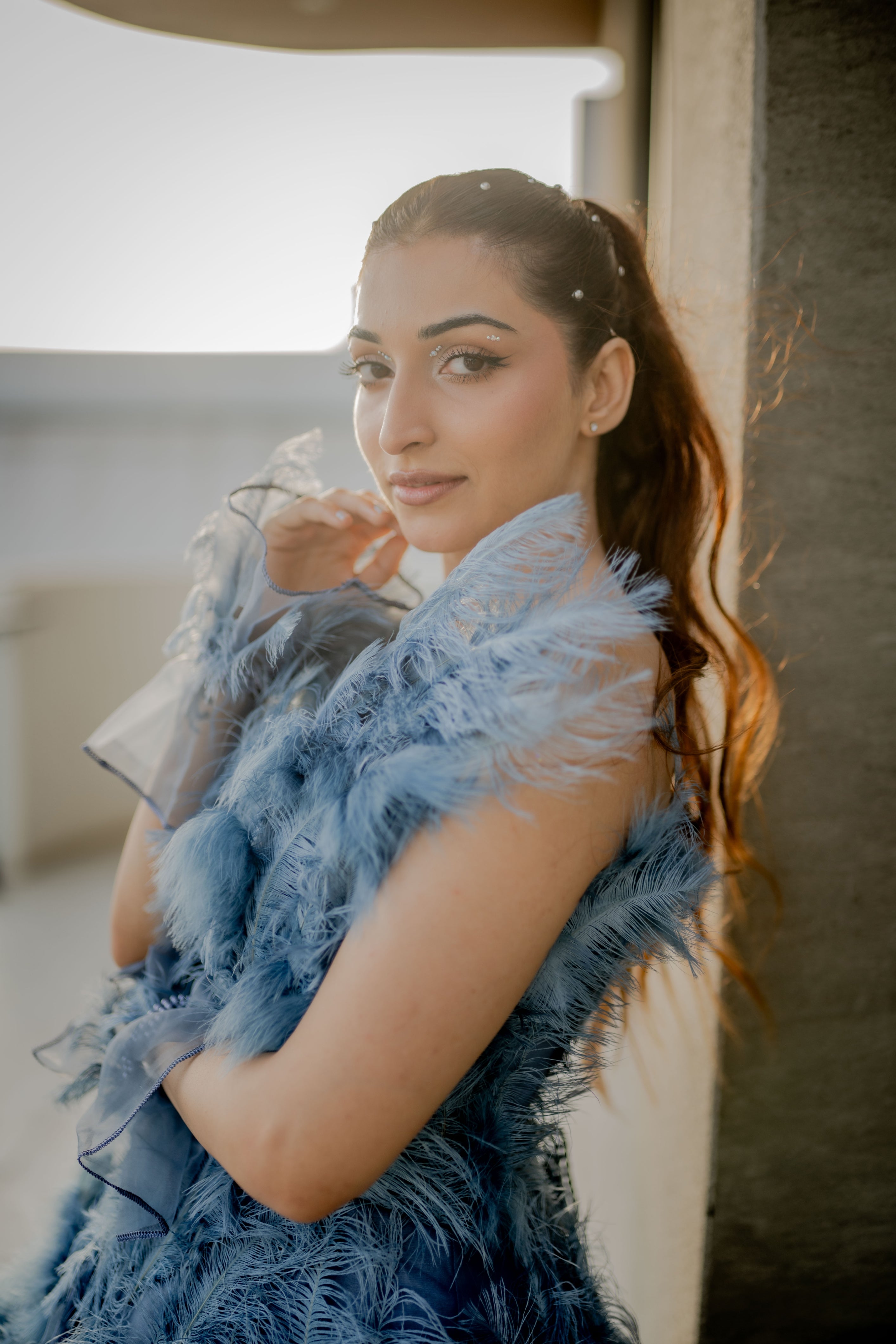 Woman wearing a blue feathered garment indoors