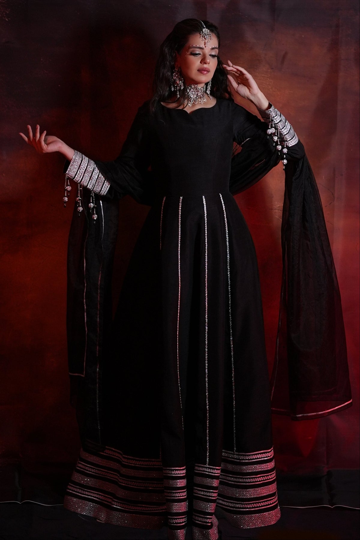 Woman in a black traditional outfit with white patterns against a dark background