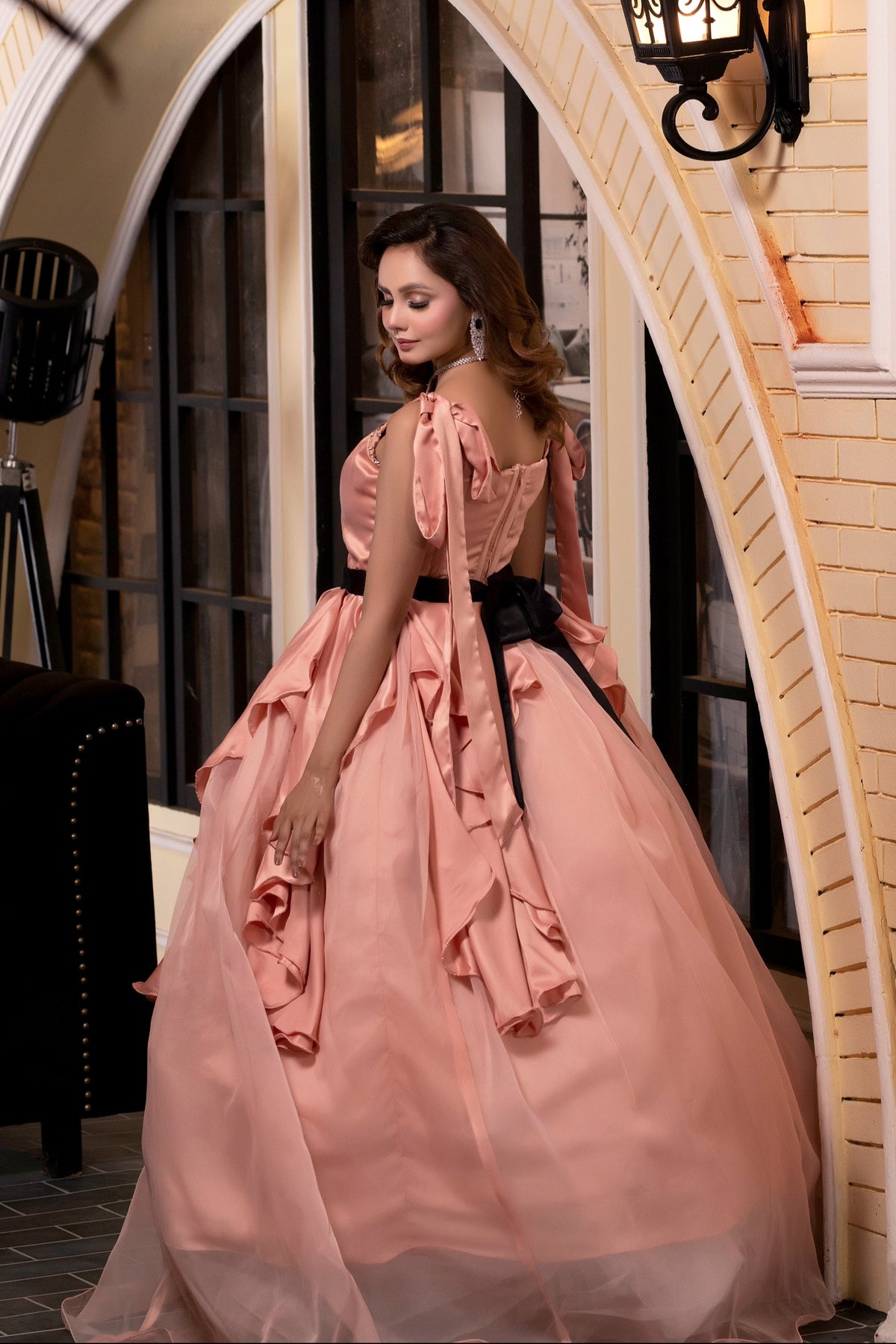 Woman in a pink dress standing in an archway with decorative elements.
