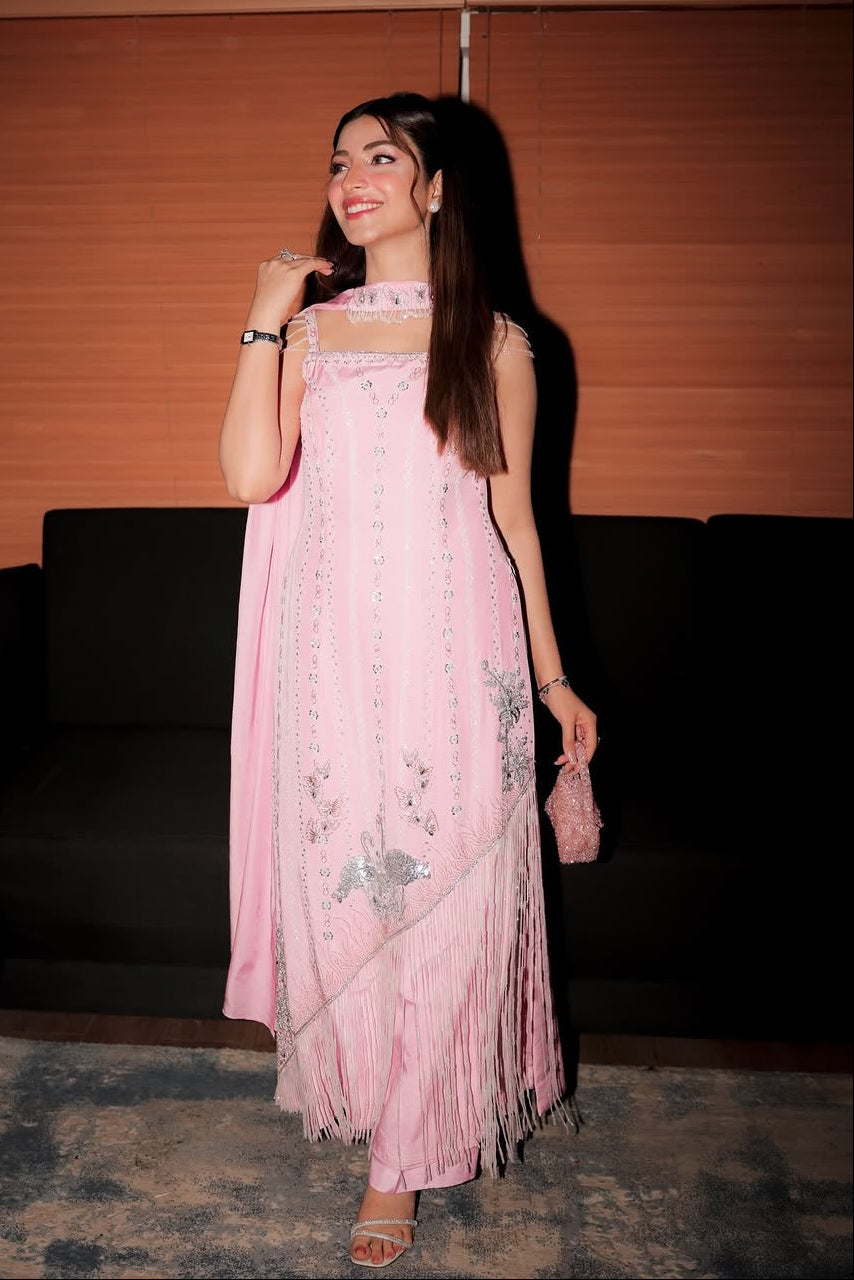 Woman in a pink dress standing indoors with a dark background