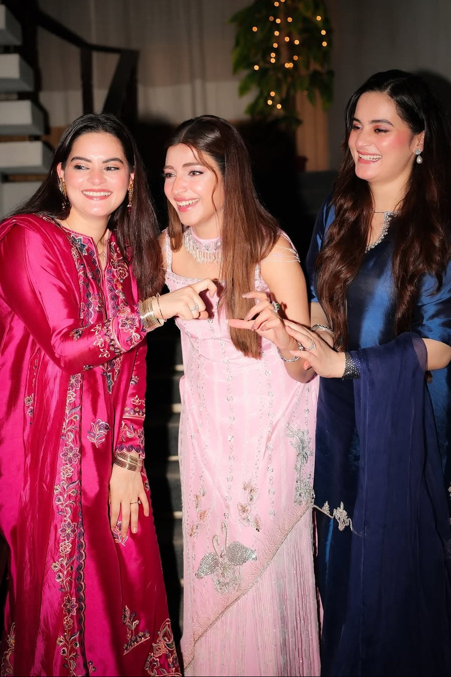 Three women in traditional attire posing together indoors.