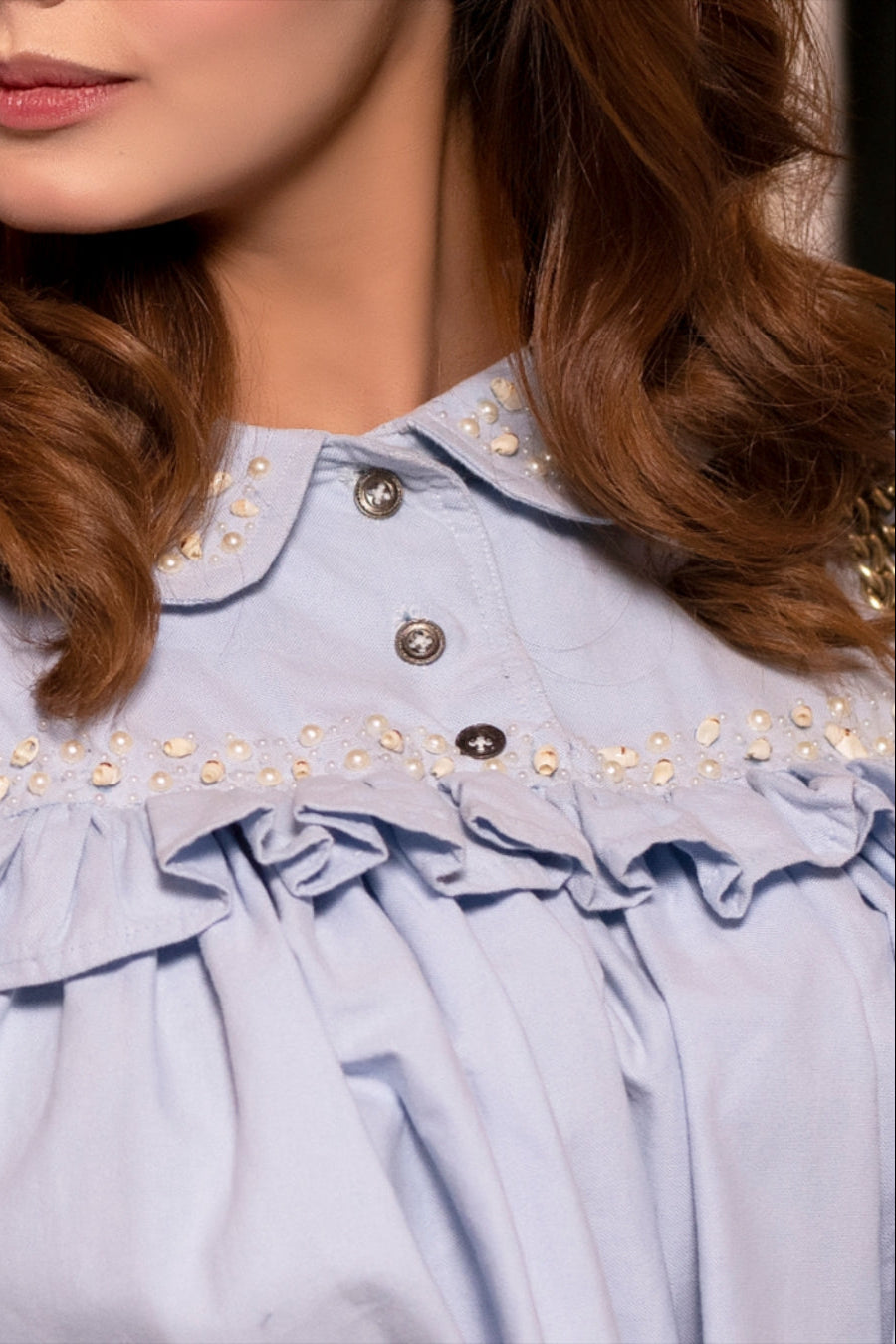 Close-up of a light blue blouse with decorative elements and a blurred background