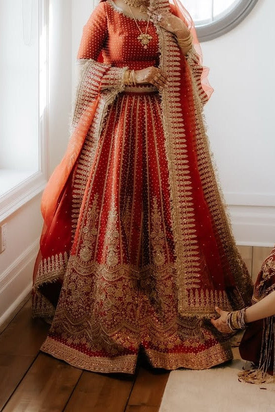 Traditional embroidered outfit with a red and gold color scheme in a room.