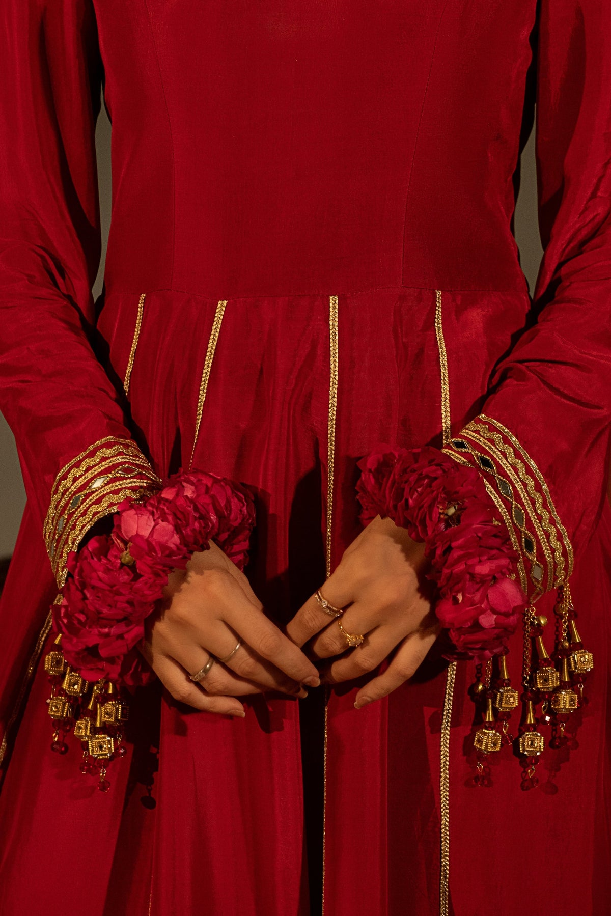 Red traditional outfit with gold embroidery and pink floral accessories.
