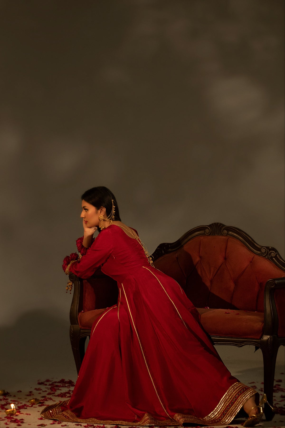 Woman in a red dress sitting on an ornate chair against a dark background