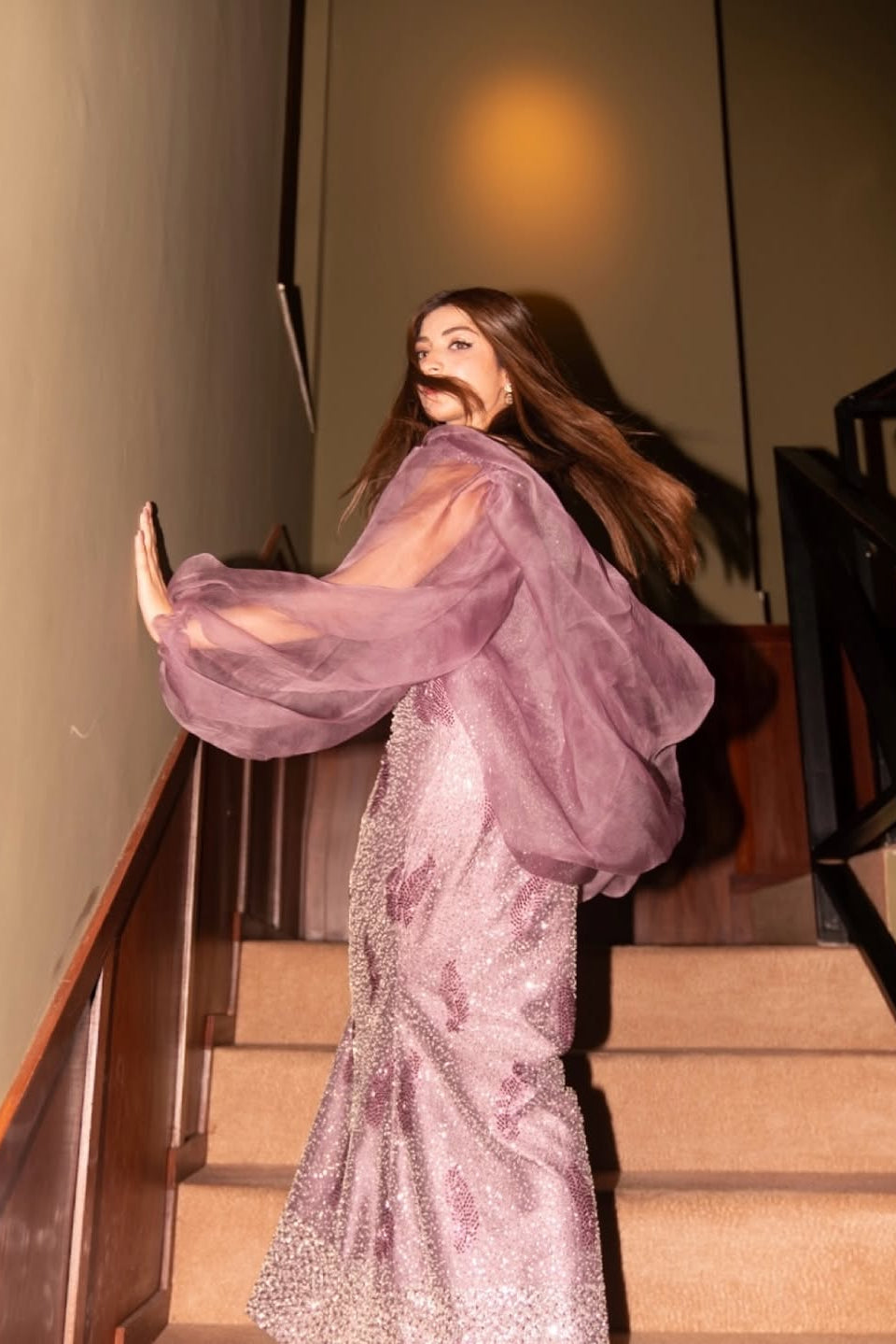 Woman in a sparkling pink dress standing on a staircase