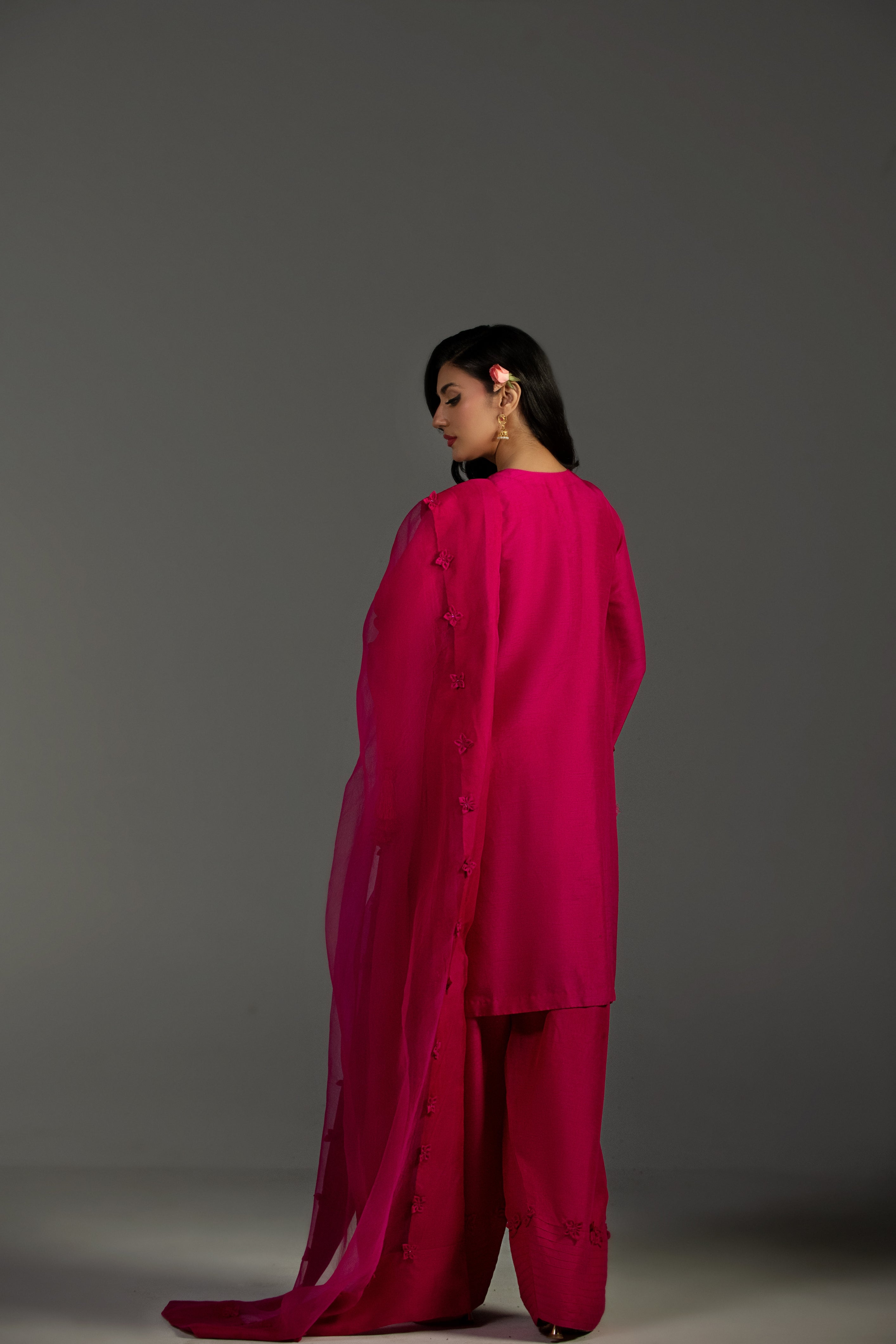 Woman wearing a bright pink outfit against a gray background