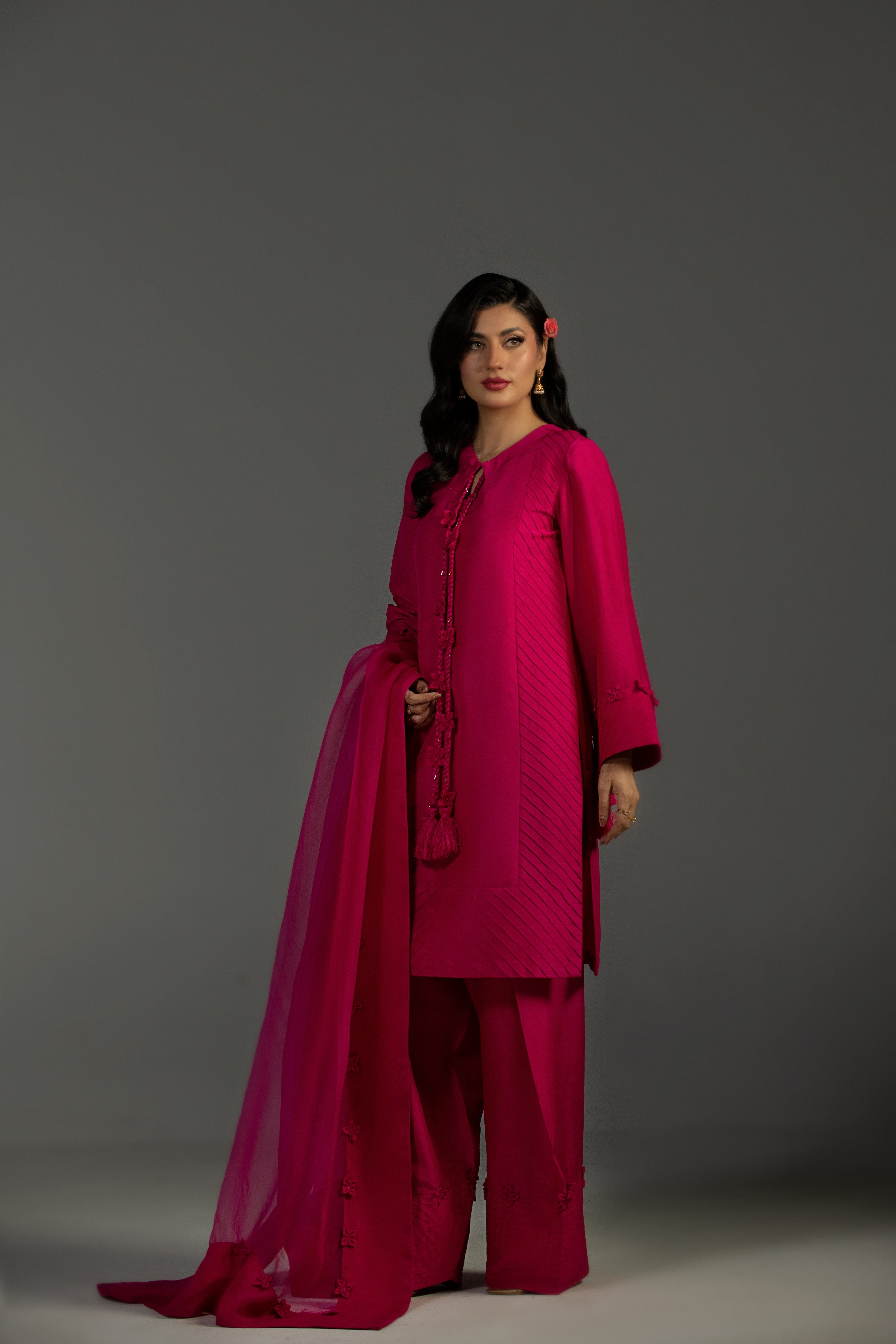 Woman wearing a bright pink traditional outfit with a gray background