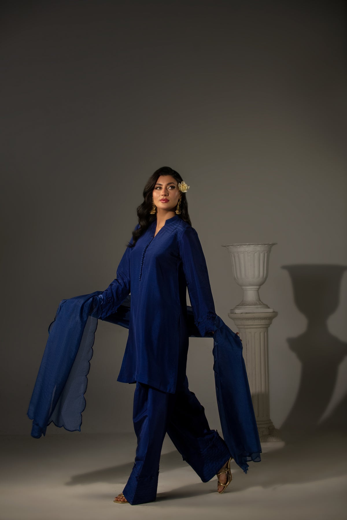 Woman in a blue outfit posing against a gray background