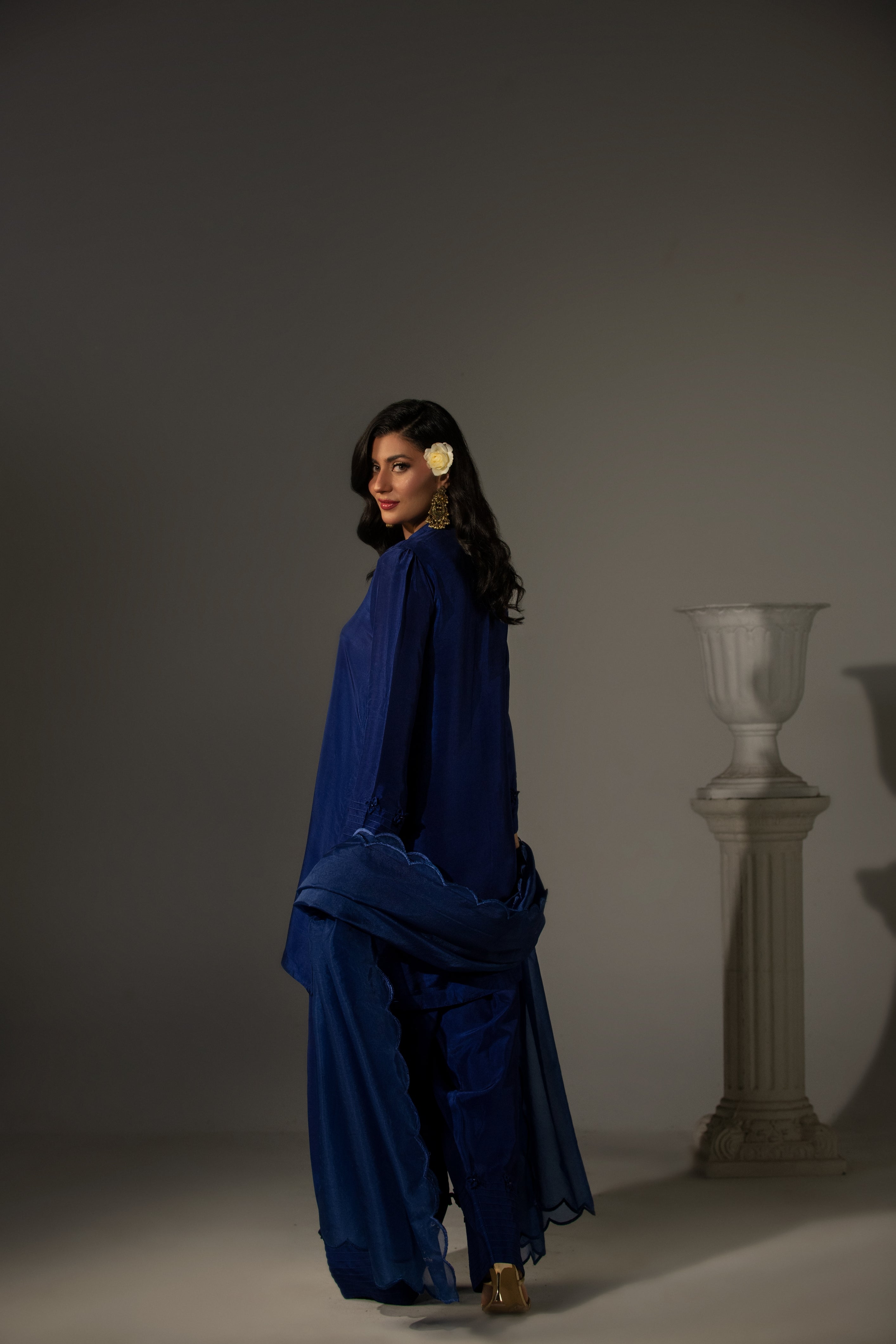 Woman in a blue outfit standing against a plain background