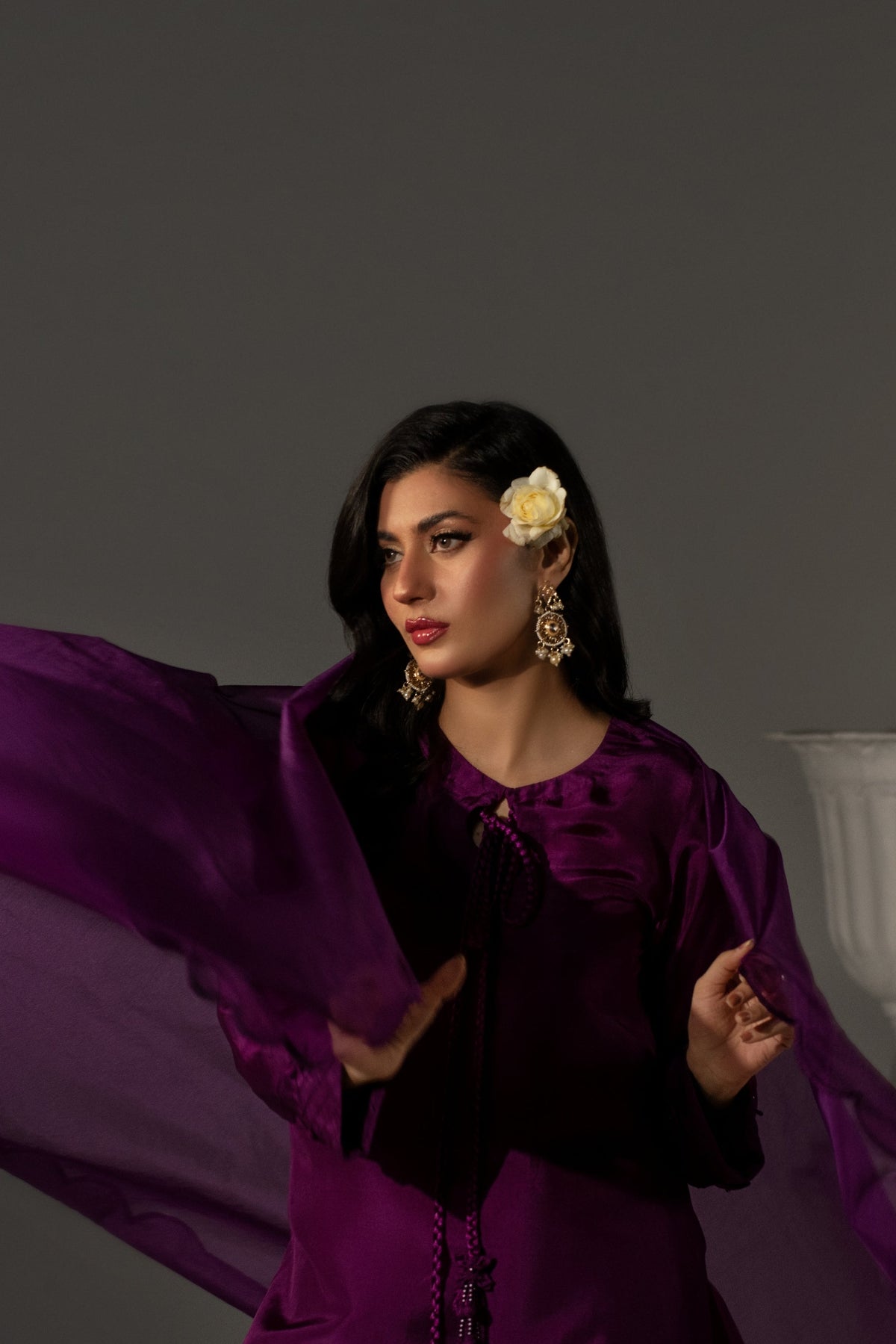 Woman in a purple dress with a white vase in the background