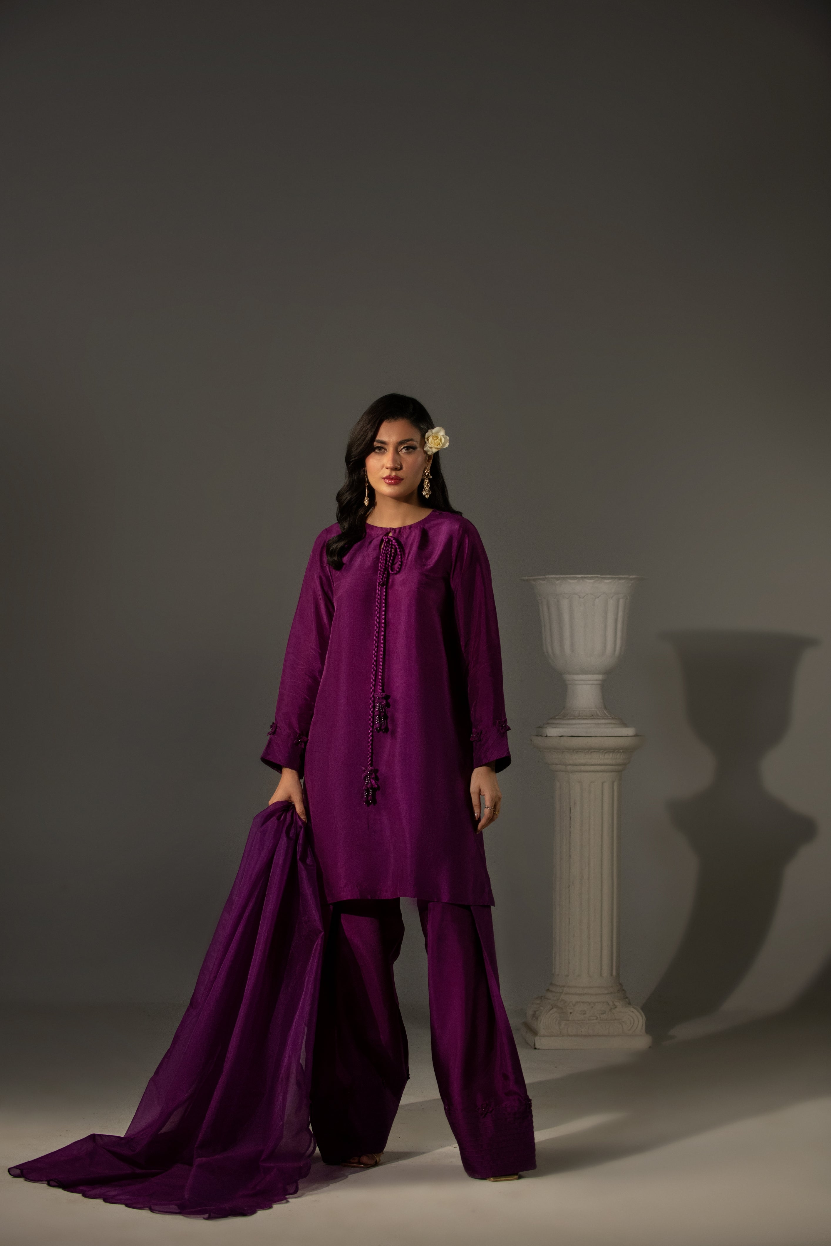 Woman wearing a purple traditional outfit against a gray background