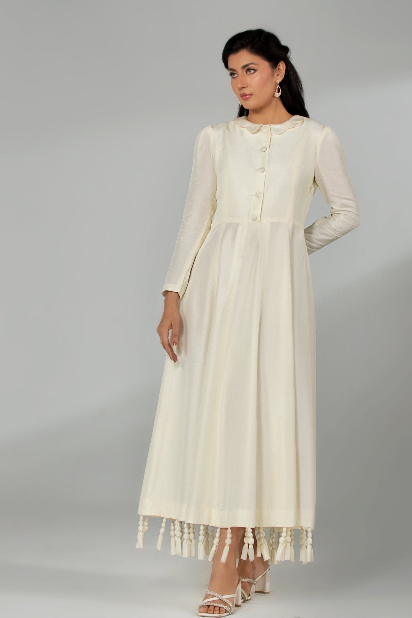 Woman wearing a white dress with fringes on a gray background