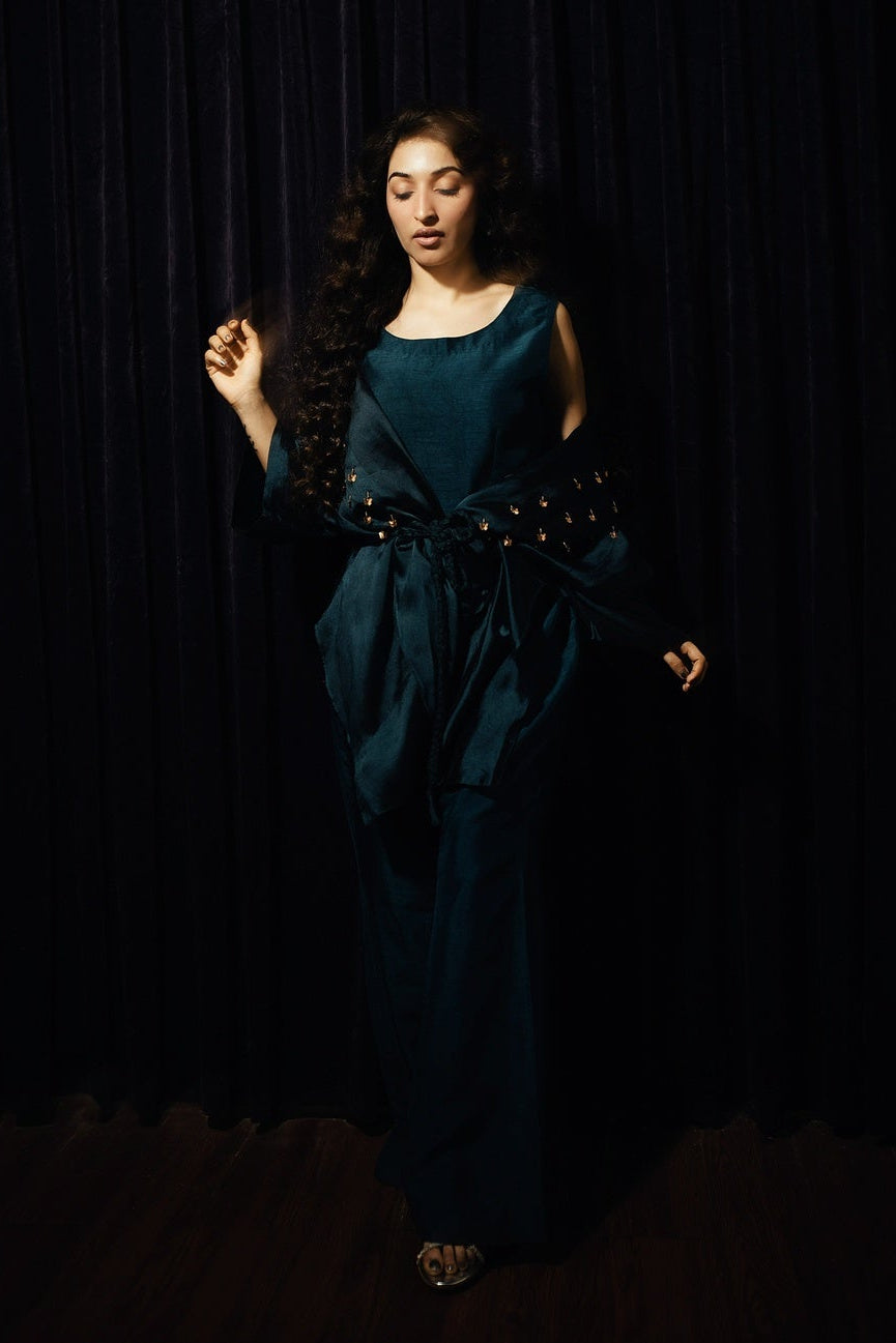 Woman in a teal dress standing against a black background