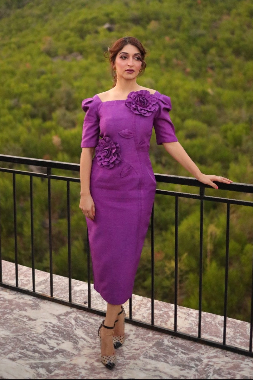 Woman in a purple dress standing on a balcony with a scenic background