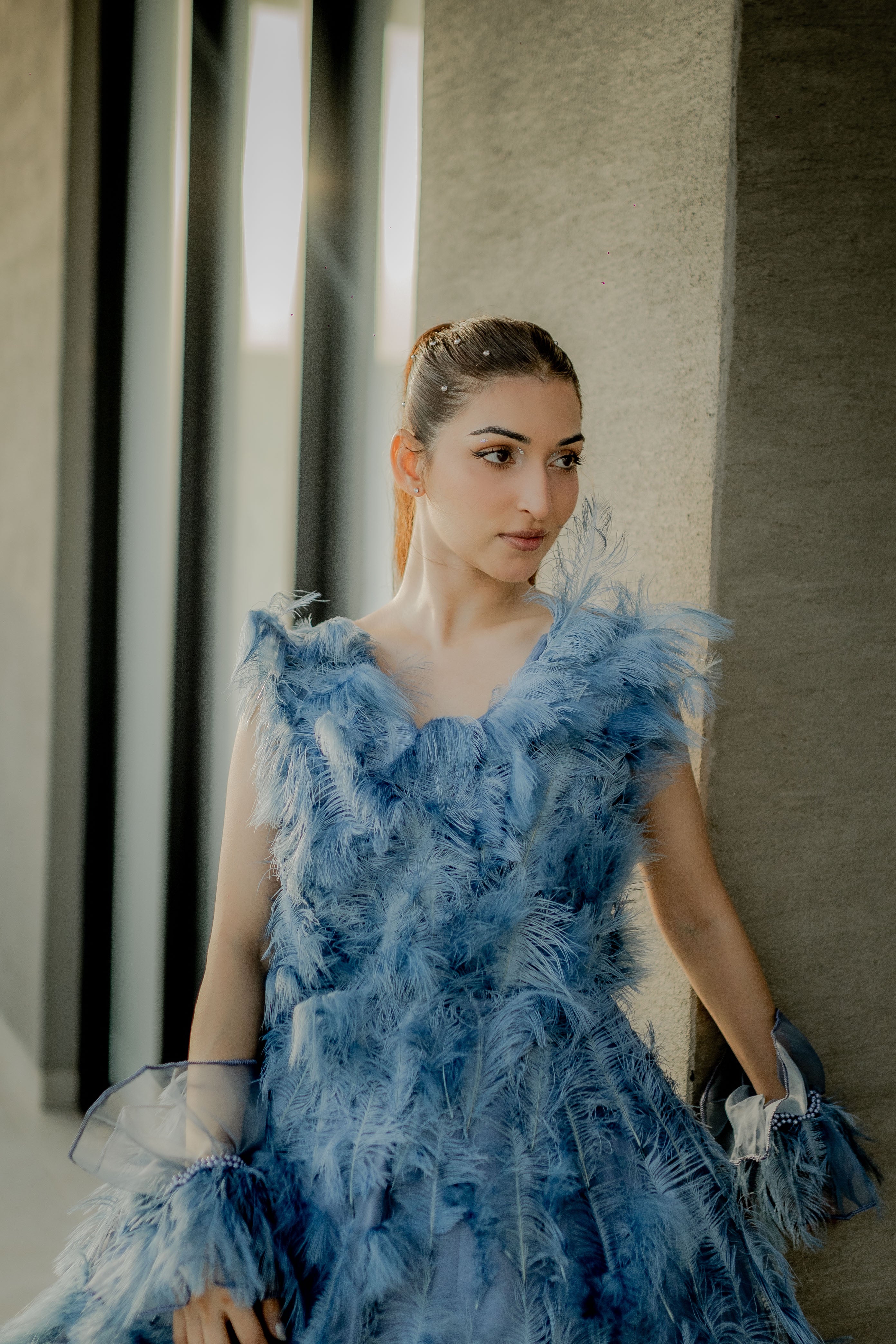 Woman wearing a blue feathered dress in an indoor setting