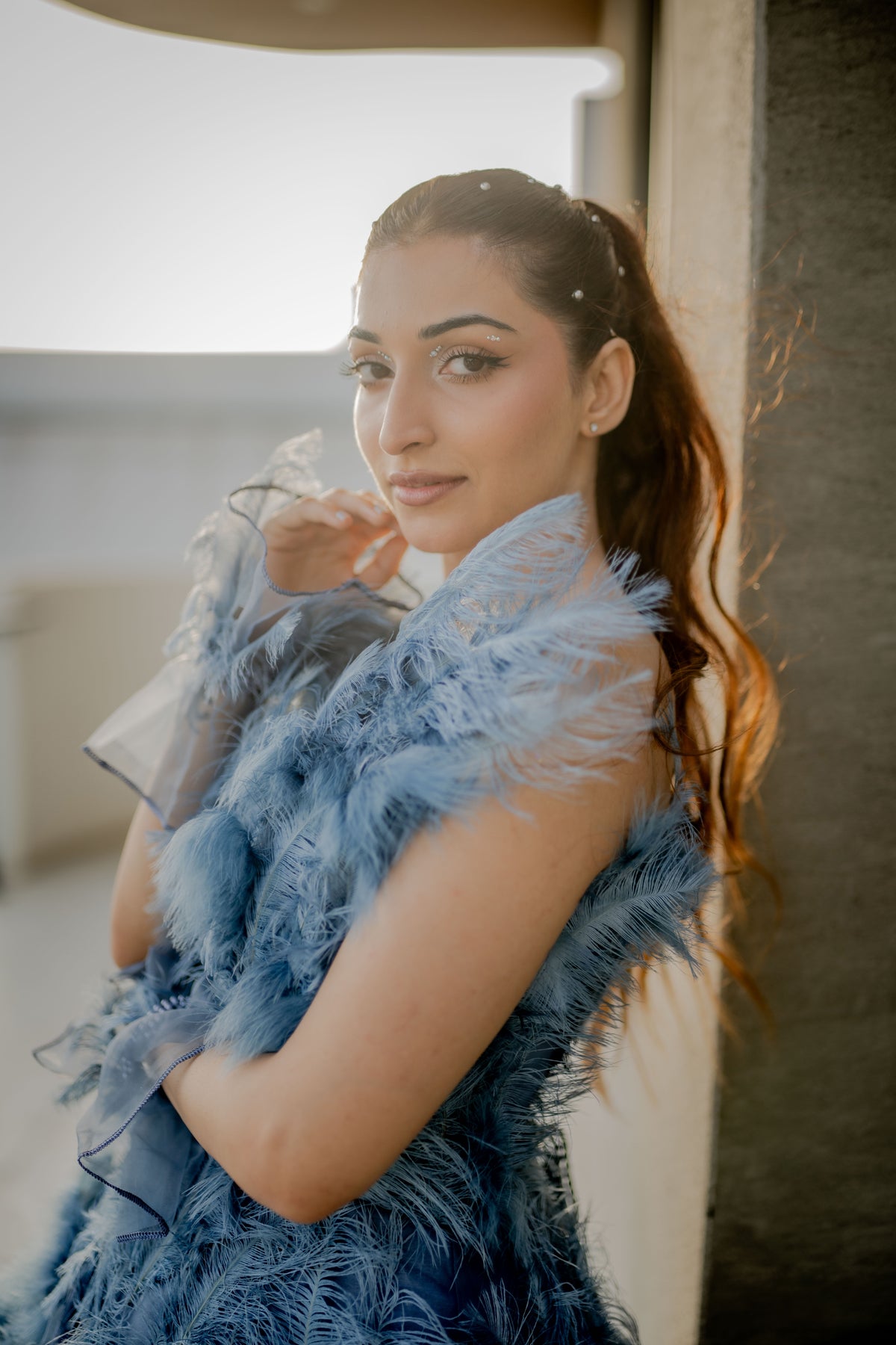 Woman wearing a blue feathered garment indoors